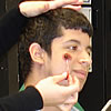 Closeup of a youth, a make-up brush being applied to his face