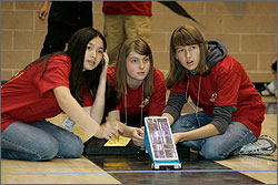 Photo of three students getting ready to race their solar car at the U.S. Department of Energy’s Junior Solar Sprint/Hydrogen Fuel Cell (JSS/HFC) Car Competition. 