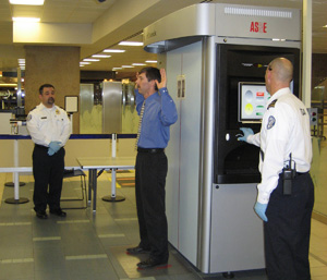 Photo of a passenger being x-rayed by two TSOs.