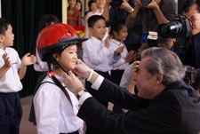 Gutierrez places safety helmet donated by an American firm on six year old Vietnamese girl. Click here for larger image.
