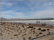 A photo of a solar field taken from the cooling tower looking northeast. The solar field is stowed (facing the ground) because the plant is still under construction. The aluminum structure of the Solargenix SGX-1 collector can be seen.