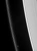 Prometheus speeds ahead of two dark gores in the F ring's inner edge. The ring's bright core swerves and twirls in its wake