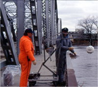 USGS technicians collecting water samples from a bridge for a reconnaissance of herbicide concentrations in streams.