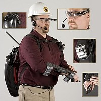 a man wearing a backpack, keyboard, camera, video viewer, and microphone attached to him