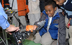 Photo of elementary school student playing with humanoid robot