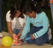 two female students kneeling down to work on their jettoy for the competition