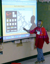 an elementary student standing at the board points to a mathematical image projected onto the screen