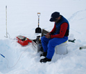 Photo of researcher Joel Harper making measurements on water flow through snow.