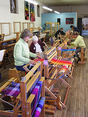           Room of women working on looms in a weaving workshop  												