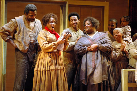 Men and women cast members onstage surrounding the lead singer		