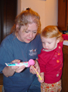 A grandmother helps her granddaughter brush her teeth.