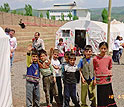 Children stand outside their makeshift classroom in the post-earthquake military tent city.