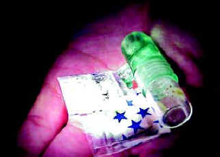 Picture of a person's open hand holding a colored vial of Ketamine powder.