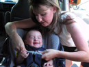 Mother puts child into carseat.