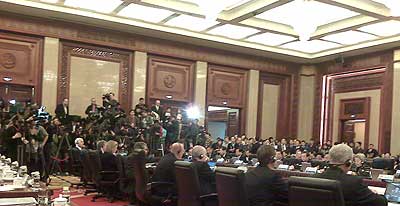 wide photo showing the plenary meeting hall, a large group of people against one wall