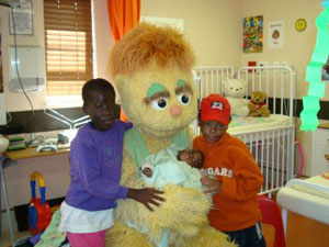 Takalani Sesame character Kami greets children at Soweto Hospice - Click for high-resolution, print-quality photo