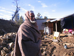 Mumtaz Alisha, a village elder salvages items from rubble to add to his new shelter home.