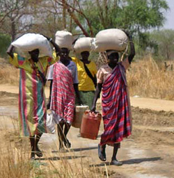 Sudanese women carry supplies down a dirt road near Bor