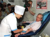 Ambassador Kirby donates blood surrounded by photographers