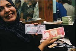 Photo: Iraqi woman shows the new currency in her country compared to the currency of Saddam Hussein.
