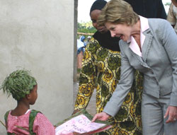 Photo of: The First Lady receives a 'Gift for Madam Laura' from a young student of Al-Rahma madrasa, who was wearing an eye-catching hat and dress that had been crafted from leaves.