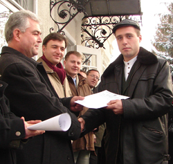 Edinet Mayor Leonid Jidacevschii, left, hands the first trade license issued by the city’s one-stop shop to retailer Alexandru Micenco.