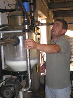 As morning milking starts, Osman Mazreku makes sure the pumps move the milk to the tank outside the barn.