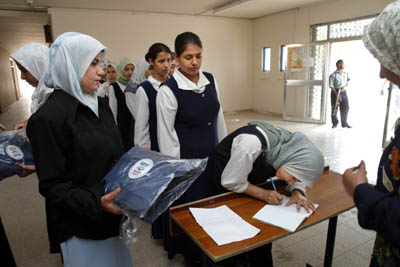 Students from the Hala Bint Khuwaylid secondary girl's school in the Amil district of Baghdad sign for and receive school bags which contain, pens, pencils, notebooks, a calculator and other school supplies. USAID is funding the purchase and distribution of 1.5 million of the bags through a contract with Creative Associates Internaitonal. All Iraqi secondary students will receive the bags.