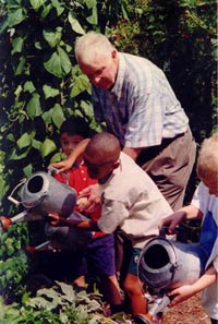 Older man and children watering plants. - Copyright (2000 or subsequent years), Generations United. Reprinted with permission of Generations United (http://www.gu.org).