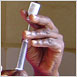 Hands fill a syringe with DMPA