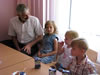 Kindergarten students and their older sisters host Mission Director Michael Farbman at their table following the dedication ceremony.