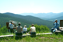 Photo: Staff members on a green mountain hillside observing a presentation.