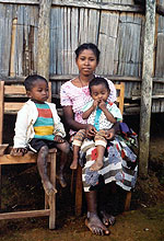 Photo of a young woman holding her children on her lap.