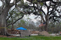 A flag waves over neatly piled bricks where a house once stood