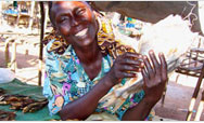 Esther Moriba selling fish at her stand in the local market - Click to read this story