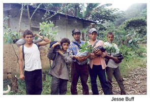 Five young men standing in front of a building in the forest and holding small trees and plants. Photo Source: Jesse Buff