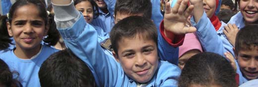 Photo of about Lebanese children smiling and waving outside of their newly repaired school.