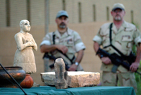 U.S. Special Forces officers guard antiquities, including a red 8,000-year old Iraqi clay pot from before the wheel was invented, during a press conference at the Iraqi national museum in Baghdad, May 16, 2003. The standing statue is one of earliest known Sumarian freestanding statues, dated around 2,700 BC. (AP Photo)