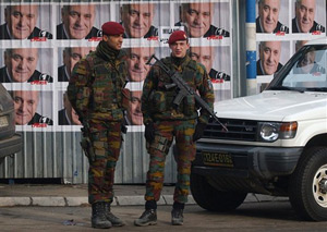 Belgian NATO soldiers in Kosovo stand in front of posters for the recent Serbian elections.