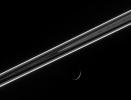 The dark side of the ringplane glows with scattered light, including the luminous F ring, which shines like a rope of brilliant neon. Below, Dione presents an exquisitely thin crescent