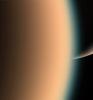 Cassini peers around the hazy limb of Titan to spy the sunlit south pole of Saturn in the distance beyond
