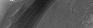 This MOC image shows a nearly ice-free view of layers exposed by erosion in the north polar region. The light-toned patches are remnants of water ice frost
