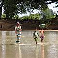 A woman and children crossing the river at the border between Ghana and Burkina Faso.
