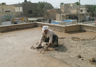 USAID partner, Save the Children, is working with community leaders to identify projects, both large and small, that will benefit the local community, including this Kindergarten rehabilitation project in the Abu Khaseeb district of Basra, Iraq. An Iraqi worker applies a mud and straw mixture to the roof of the kindergarten which would not support heavier cement re-inforcement. The project was funded by a grant from USAID and contributions from the community.