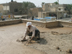 USAID partner, Save the Children, is working with community leaders to identify projects, both large and small, that will benefit the local community, including this Kindergarten rehabilitation project in the Abu Khaseeb district of Basra, Iraq. An Iraqi worker applies a mud and straw mixture to the roof of the kindergarten which would not support heavier cement re-inforcement. The project was funded by a grant from USAID and contributions from the community.