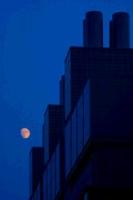 Moon next to building.