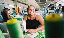 Photo of a Brazilian seamstress at her sewing machine in a swimwear firm.