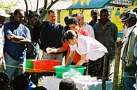 Photo of Dr. Peterson dipping a mosquito net at a demonstration as USAID mission director in Ethiopia William Hammink and others look on.