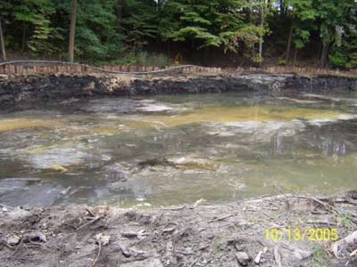 A section of original streambed that has been excavated to a depth that removed the contaminated sediment that was present. Note that sheet piling is installed in the background to protect the creek bank from collapse. Also note the pipeline draped over the sheet piling which conveys contaminated drainage from a drying bed. This is pumped all the way to treatment plant at the Pond.