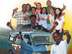 Image of a Guyanese billboard with a minibus and people demanding respect for those living with HIV/AIDS.